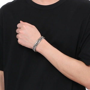 Close-up of men's silver stainless steel double-woven Cuban link bracelet on wrist