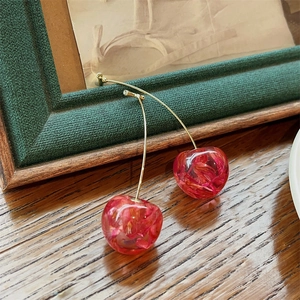 Artistic close-up of cherry earrings with dried flower filling on a wooden surface
