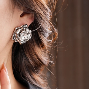 Gros plan d'une boucle d'oreille rose argentée avec cristal carré sur l'oreille
