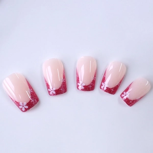 Pink French press-on nails with red glitter tips and white flower designs for women