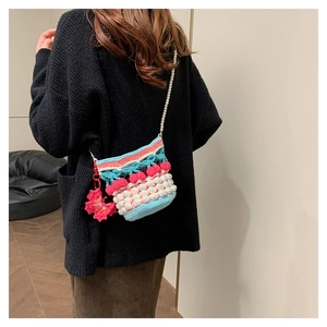 Detail of crochet knit bucket bag with cherry pattern and elegant pearl strap