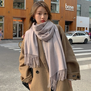 Thick solid light purple cashmere scarf with tassels worn over a brown wool coat