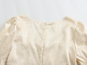 Détail d'une robe en jacquard floral blanc crème avec fermeture éclair et manches bouffantes