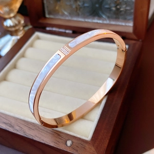 Macro detail of rose gold titanium bangle with white shell inlay and three zircon stones