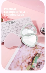 Close-up of heart-shaped folding pocket mirrors in pink and green on a desk