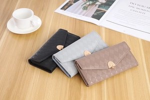 Three elegant quilted PU leather envelope wallets on a wooden desk with a coffee cup