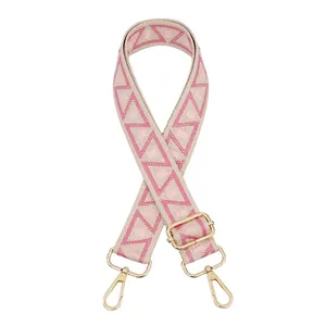 Close-up of adjustable woven purse strap with pink geometric jacquard and gold metal hooks