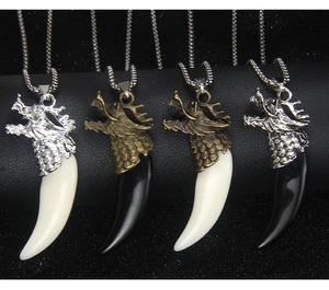 Detail view of dragon head pendants with acrylic wolf fangs in silver and bronze finishes