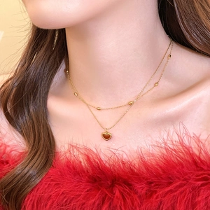 Close-up of double-layered gold heart pendant necklace with beads on female model