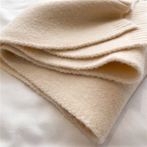 Detailed close-up showing the soft texture and knit pattern of the beige scarf