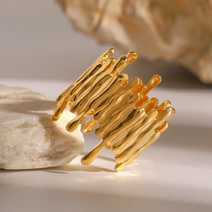Irregular gold wavy open ring made of polished stainless steel on a natural stone base