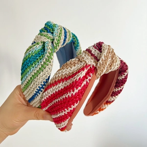 Détail de serre-têtes en paille tressée montrant la texture du tissu et le nœud central