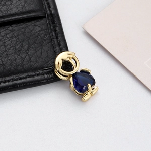 Detail shot of a golden boy pendant with a teardrop dark blue zircon for DIY jewelry