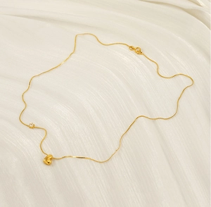 Close-up of gold heart necklace with a round zircon on white silk background