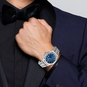 Classic silver metal watch on male model wearing blue suit for professional business style