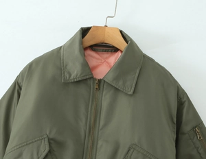 Detailed shot of olive bomber jacket with pink quilted lining and metal zipper
