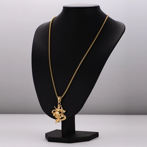 Gold stainless steel box chain necklace with snake and dagger pendant on a black bust