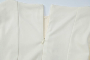 Detailaufnahme des verdeckten Rückenreißverschlusses und Faltenhalsausschnitts am cremeweißen Kleid