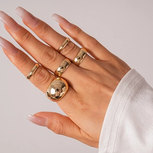 Detail of 5-piece gold geometric ring set styled on hand with modern polished finish