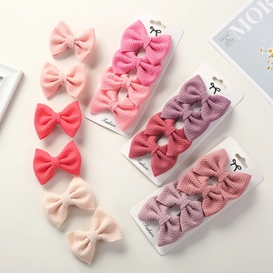Detailed set of waffle fabric bow clips in pink, purple, and beige on card packaging