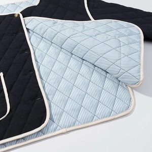Close-up of black quilted jacket with blue stripe lining and golden button detail