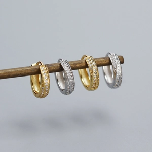 Close-up of gold and silver S925 Mobius hoop earrings with sparkling zircon inlay