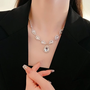 Vue macro d'un collier pendentif goutte en argent avec cristaux sur un blazer noir