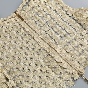 Detail view of gold floral embroidery and metallic zipper on a two-piece dress set