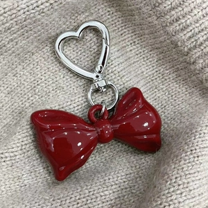 Close-up of a red acrylic bow keychain with a silver heart-shaped metal clasp