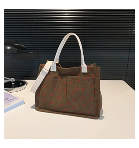 Close-up of brown corduroy tote bag with red strawberry pattern and functional front pockets