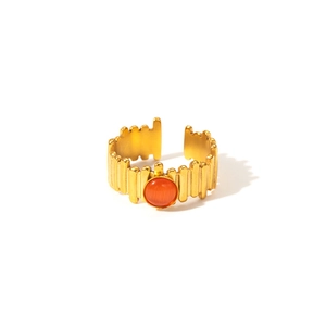 Detail view of gold titanium ring with orange natural stone and gear pattern texture