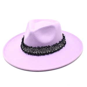 Détail d'un chapeau fedora en laine lilas avec ruban décoratif en tweed noir et blanc