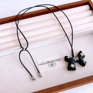Macro shot of retro starburst wooden bow pendant on black cord in jewelry display tray