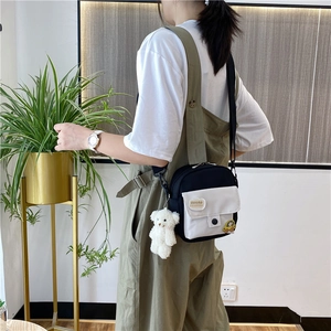 Sac bandoulière en toile bicolore avec pendentif ours en peluche sur modèle