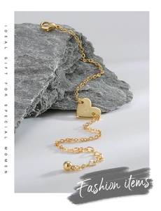 Détail macro du bracelet doré avec pendentif cœur gravé lettre D et fermoir homard