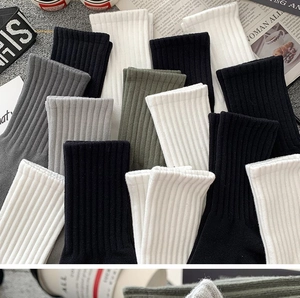 Flat lay of cotton ribbed crew socks in white, black and grey tones with fashion magazine