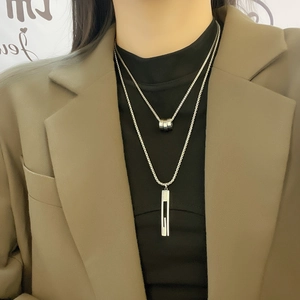 Detail of silver double-layer titanium steel necklace with rectangular hollow pendant on model
