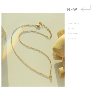 Macro detail of 18K gold plated necklace with a single cubic zirconia pendant and clasp