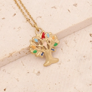 Detail of golden tree of life pendant with colorful stones on a textured stone surface