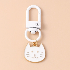Close-up of a white cat metal keychain with a white spring hook and golden outlines