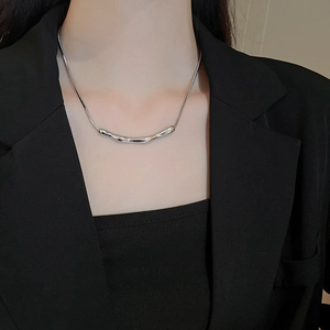 Details einer silbernen unregelmäßigen Halskette auf einer Schlangenkette über Blazer
