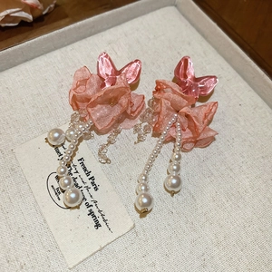 Detail of pink floral crystal tassel earrings with translucent butterfly and soft petals