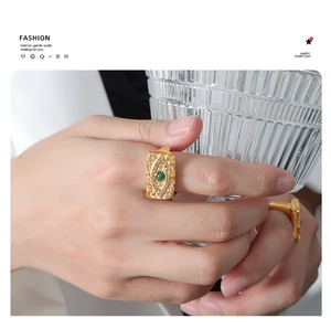Macro shot of vintage gold rectangular ring with green gemstone and evil eye detail
