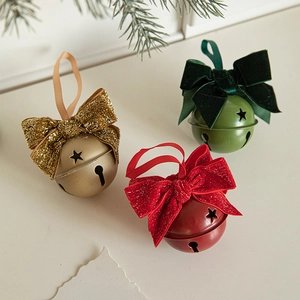 Christmas velvet bow metal bells in gold, red and green hanging on pine branch background