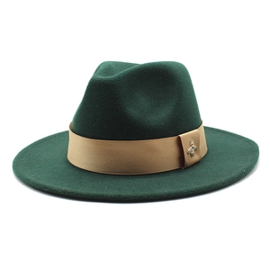Detail of dark green wool fedora hat with khaki band and gold bee accessory