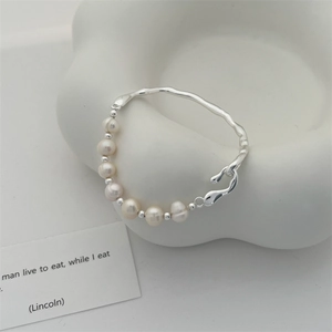 Macro detail of Baroque freshwater pearl joined with irregular silver branch bracelet