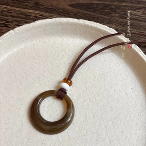 Dettaglio macro della collana con ciondolo cinese circolare in giada marrone su piatto