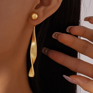 Close-up of matte gold twisted drop earrings with pearl stud on a model for a stylish look
