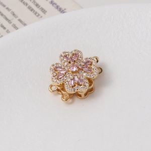 Detailed macro of golden rotating flower clasp with micro-set cubic zirconia and pink stones