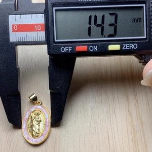 Measuring 14.3mm width of golden oval Jesus pendant with pink mother of pearl shell